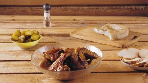 Human hand puts a plate with fried chicken wings on a wooden table Stock Footage 171885902