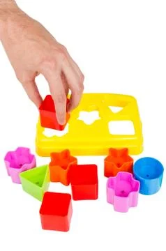 Human hand puts wrong shape into shape sorter toy isolated Stock Photos