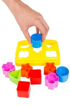 Human hand puts wrong shape into shape sorter toy isolated Stock Photos
