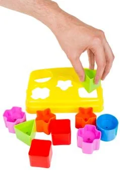 Human hand puts wrong shape into shape sorter toy isolated Stock Photos