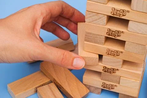Human hand removing one block from Jenga tower Stock Photos