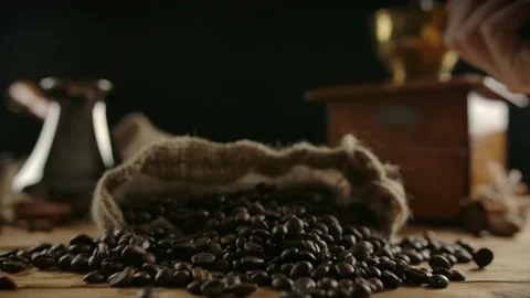 Human hand scattering roasted coffee beans from fistful over burlap sack Stock Footage 138521391