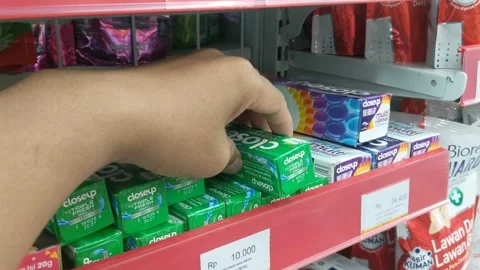 Human hand selecting a toothbrush and toothpaste on a figure shelf Stock Footage 265074943