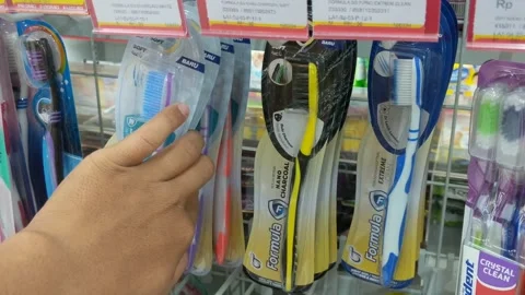 Human hand selecting a toothbrush and toothpaste on a figure shelf Stock Footage 265074947