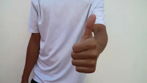 A human hand showing a thumbs up gesture against a plain white background. Stock Footage 344563514