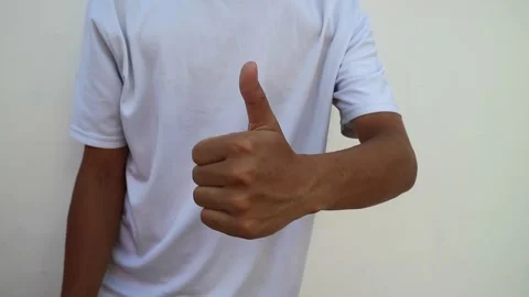 A human hand showing a thumbs up gesture against a plain white background. Stock Footage 344563567