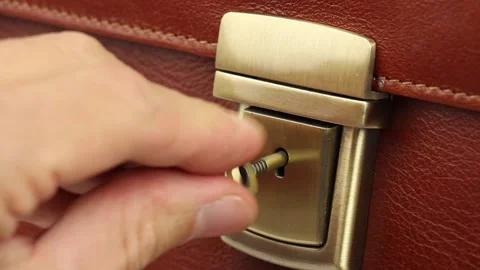 Human hand with small key open lock on gold buckle leather briefcase Видео 145535874