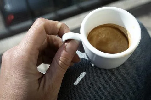 Human hand with small white empty cup espresso coffee in bright sunlight Stock Photos