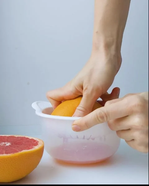 Human hand squeezing fresh grapefruit juice process, close up, front view Stock Footage 170629704