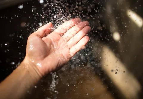 Human hand in sunlight under falling water. Foto stock
