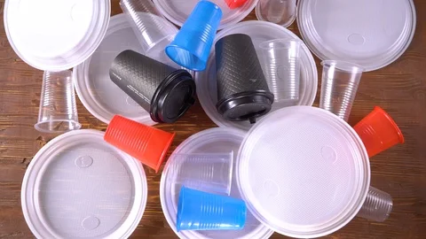 Human hand sweep away plastic utensils disposable dishes, colorful plates, cups Video stock 106344201