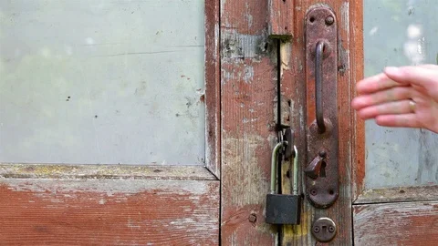 A human hand takes the door handle of a red brown rotten door Stock Footage