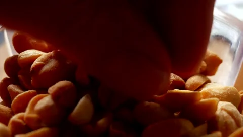 Human hand takes roasted and salted peanuts from a small transparent bowl Stock Footage 134905242