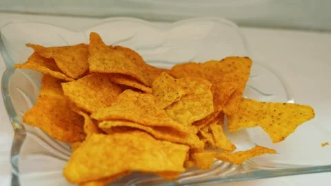 Human hand taking crispy tortilla nacho chips from a glass bowl Stock Footage 341859187
