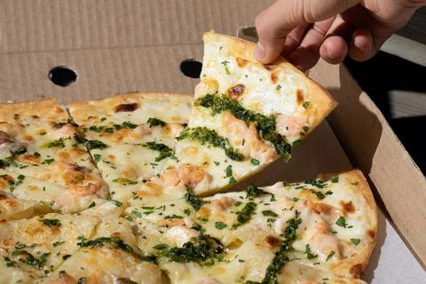 Human hand taking slice of pizza with salmon and cream cheese Stock Photos