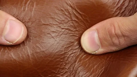 Human hand testing outer side of light brown natural smooth shiny glossy leather Stockbeeldmateriaal 135290782