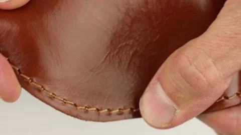 Human hand testing texture of brown or red natural smooth shiny glossy leather Видео 145535785