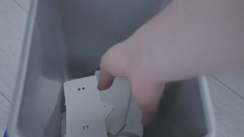 Human hand throws bunch of used paper into grey trash bin Stock Footage 267745199