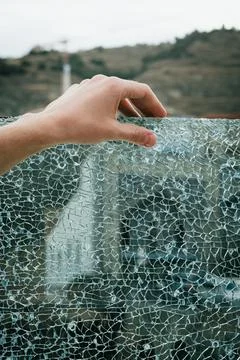 A human hand touches the web-like pattern of shattered safety glass, with 库存照片