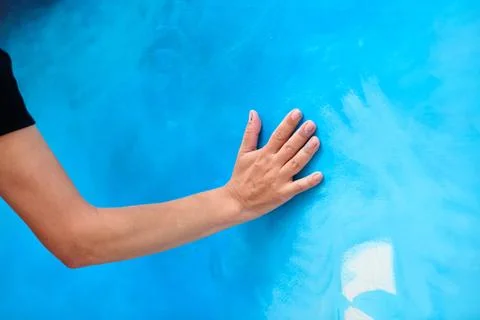 Human hand touching bright blue canvas surface with subtle brush texture Stock Photos
