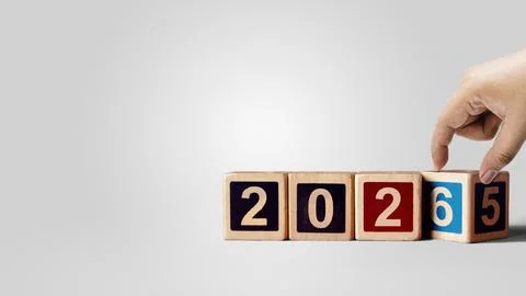 Human hand transforms wooden cubes from the number 2025 to 2026 on a white .. Stock Photos