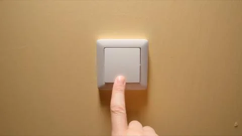 Human hand turn off a power button on a yellow wall Stock Photos