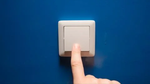 Human hand turn off a power button on a blue wall Stock Photos