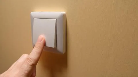 Human hand turn off a power button on a yellow wall - side view Stock Photos