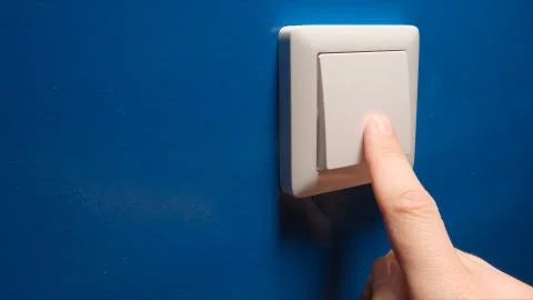 Human hand turn off a power button on a blue wall - side view Stock Photos