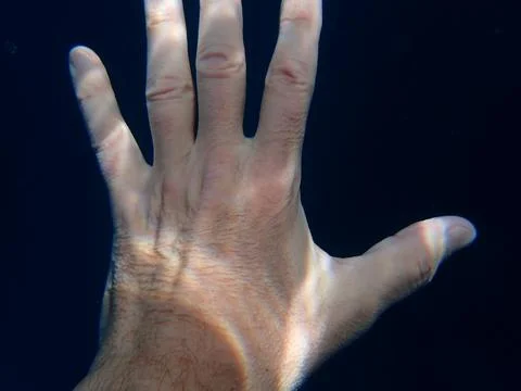 Human hand underwater with abstract light patterns on skin Photos