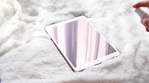 Human hand uses and puffs an antibacterial agent on the electronic tablet screen Video stock 127626005