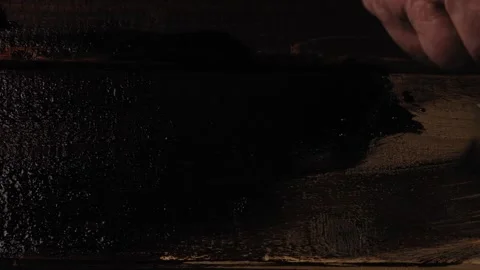A human hand uses a brush to cover the boards with dark brown paint Stock Footage 280266256