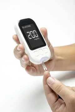 Human hand using a glucometer for checking blood sugar level isolated over .. Foto stock