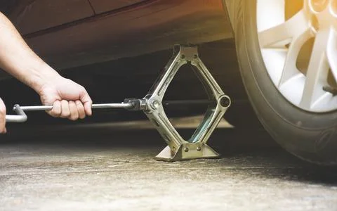 The human hand is using a jack lift to the car body Foto stock