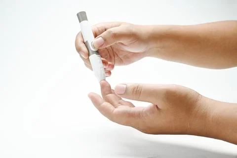 Human hand using a lancet for checking blood sugar level isolated over a wh.. 写真素材