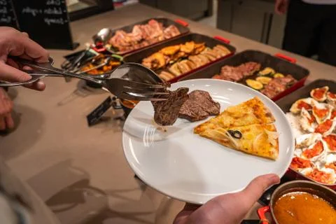 Human hand using tongs picking beef steak into his plate Stock Photos