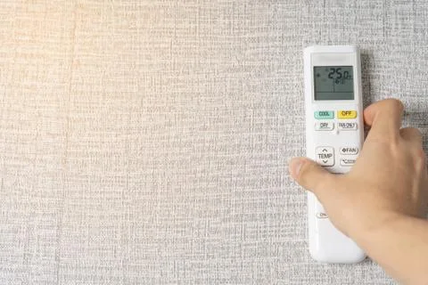 Human hand is using white remote of air conditioner for turn on or adjust tem Stock Photos