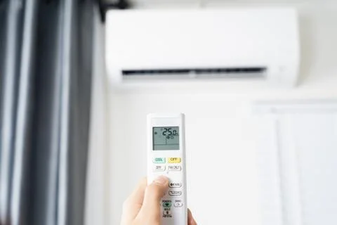 Human hand is using white remote of air conditioner for turn on or adjust tem Stock Photos