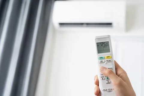 Human hand is using white remote of air conditioner for turn on or adjust tem Stock Photos