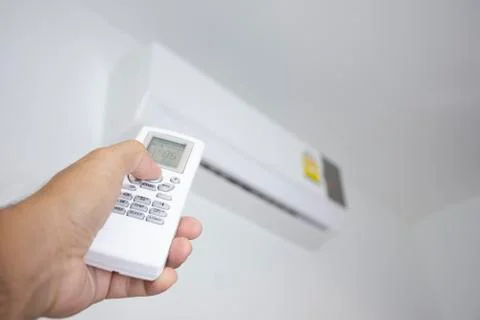 Human hand is using white remote of air conditioner Stock Photos