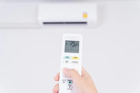 Human hand is using white remote of air conditioner for turn on or adjust tem Stock Photos