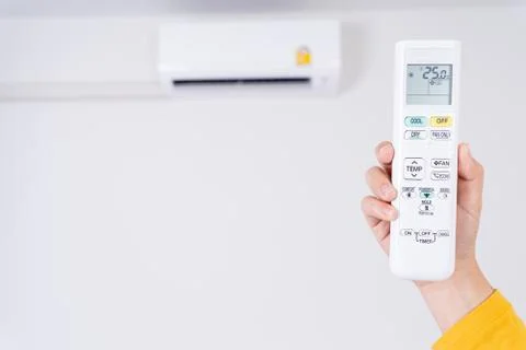 Human hand is using white remote of air conditioner for turn on or adjust tem Stock Photos