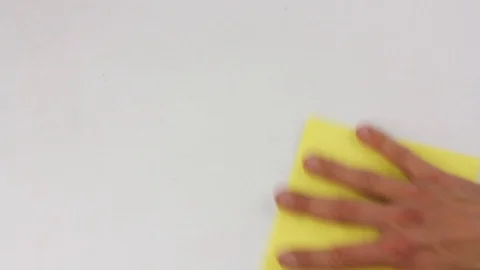 Human hand wipes and cleans the white surface of table with yellow square cloth Видео 103122673