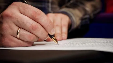 The human hand that writes text on a sheet of white paper 스톡 사진