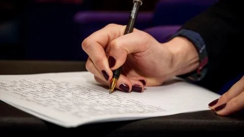 The human hand that writes text on a sheet of white paper 스톡 사진