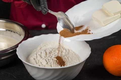 Human hands adding cinnamon to ingredients for making cookies Foto stock
