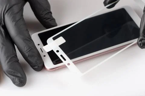Human hands are removing a protective film from the screen of a smartphone. Stock Photos