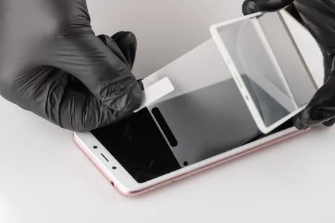 Human hands are removing a protective film from the screen of a smartphone. Stock Photos
