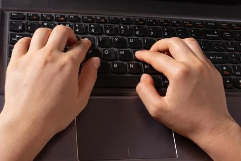 Human hands are typing text on a black laptop keyboard. Typesetter, freelance Stock Photos