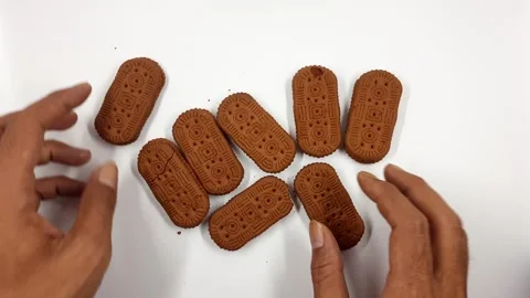 Human hands arranging brown oval biscuits on a white table motion clip. Stock Footage 330465743